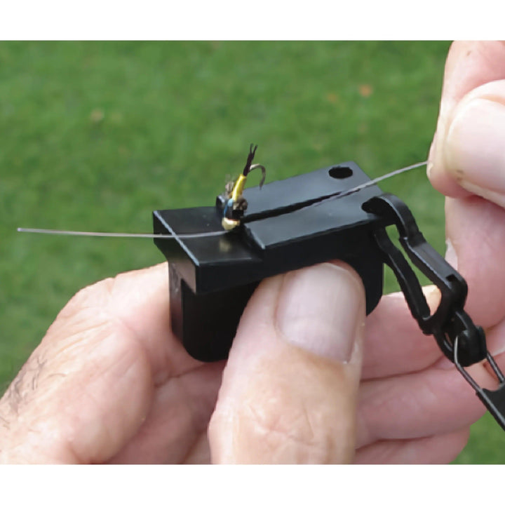 Magnetic tippet threader holding a small fly while tippet is threaded through the hook eye