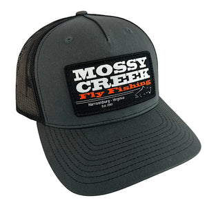 Mossy Creek Fly Fishing patch trucker hat with charcoal front and bill with black mesh and black Est. logo patch